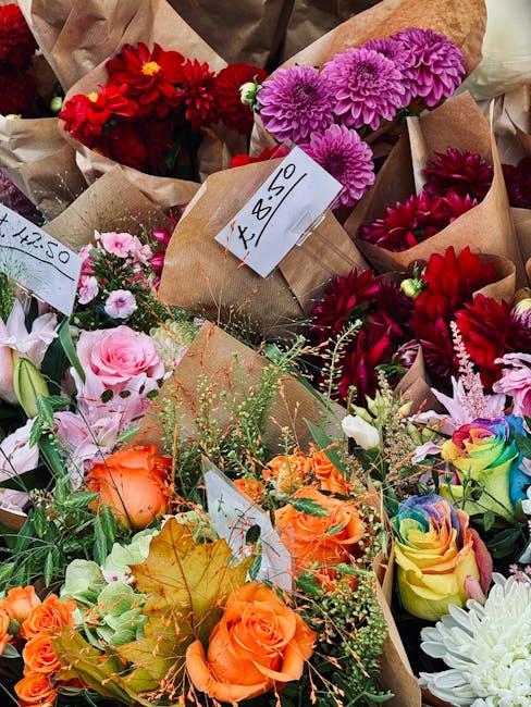 A vibrant assortment of freshly arranged flower bouquets displayed on a table, featuring a variety of colorful blooms including bright red dahlias, soft pink roses, orange roses, purple chrysanthemums