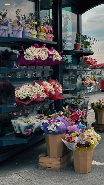 A display of various floral arrangements and bouquets at debeauvoirtownflorist.co.uk, featuring vibrant white, pink, and purple flowers, including chrysanthemums, lilies, and alstroemeria, wrapped in 