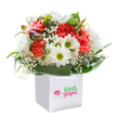 This cheerful floral arrangement, set in a crisp square white gift bag, radiates the easy sophistication of De Beauvoir Town living-bright, inviting, and just a touch daring. At its center, luxurious coral and peach carnations bloom with frilly softness, their hues reminiscent of Sunday mornings in local coffee shops. Peppered between them, pristine white daisies with vivid yellow-green centers infuse the bouquet with a zestful spark, while airy sprays of baby's breath float gently throughout, their tiny blossoms lending innocence and grace. On the left, tucked discreetly among the greenery, a few purple-edged buds add an understated layer of depth and anticipation. Encasing the vibrant blooms, broad glossy leaves form a tidy ring of fresh green, reminiscent of the lush gardens and leafy boulevards surrounding De Beauvoir Square. The white gift bag is both stylish and practical, complete with crisp ribbon handles for easy, elegant delivery across the neighbourhood. Set against a white background, the visual impact is immediate-a bouquet that offers a splash of seasonal colour, the comfort of expert design, and a heartfelt connection between florist and community. Perfect for a birthday, a new home celebration, or a spontaneous gesture of kindness for someone you care about around De Beauvoir Town.